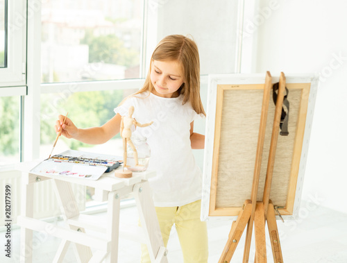 Cute little girl paints on canvas