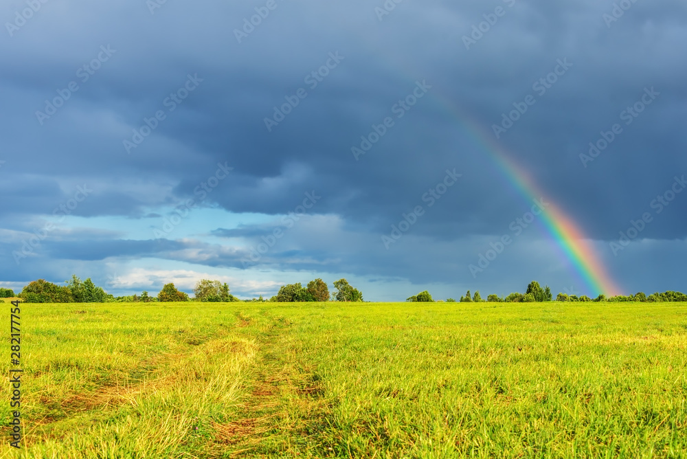 Rural landscape with dirt road and rainbow in the sky after the rain. Rural landscape with dirt road and rainbow in the sky after the rain.