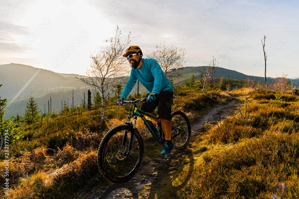 Obraz premium Cycling man riding on bike at sunset mountains forest landscape. Cycling MTB enduro flow trail track. Outdoor sport activity.