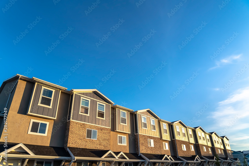 Townhouses with brick wood and concrete wall against blue sky on a sunny day