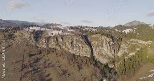 Aerial orbit around mountainous formations in Romanian countryside at sunset, during winter time. photo