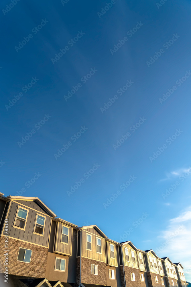 Blue sky over row of houses with wood brick and concrete exterior wall