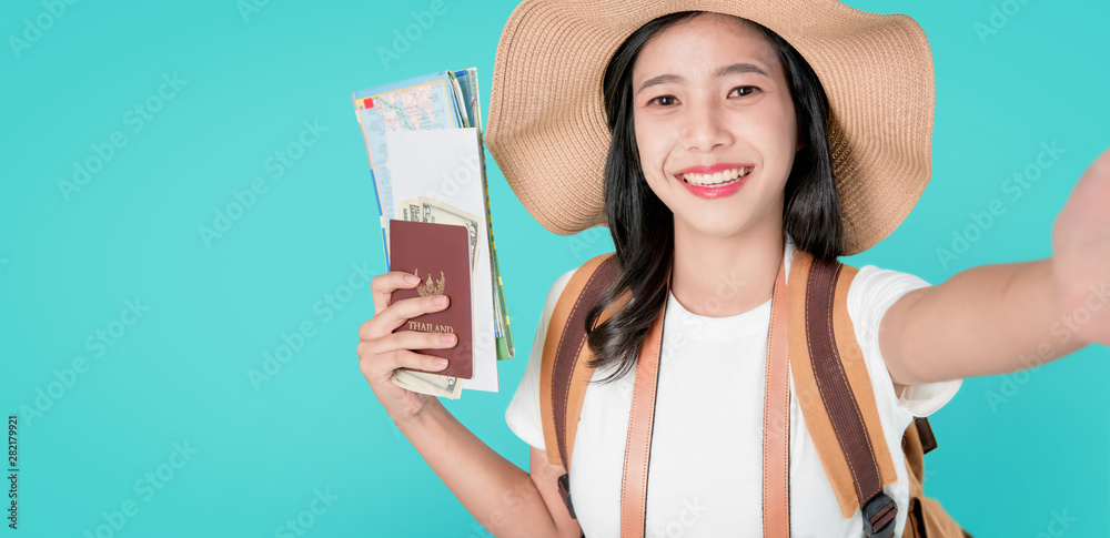 Smiling happily Asian woman traveler holding passport with ticket and map, money on blue background. Smiling happily Asian woman traveler holding passport with ticket and map, money on blue background.