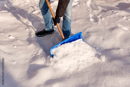 A teenager shoveling snow in his yard. The concept of a snowy winter.