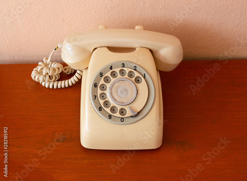A retro telephone on wood table. Front of the classic phone.