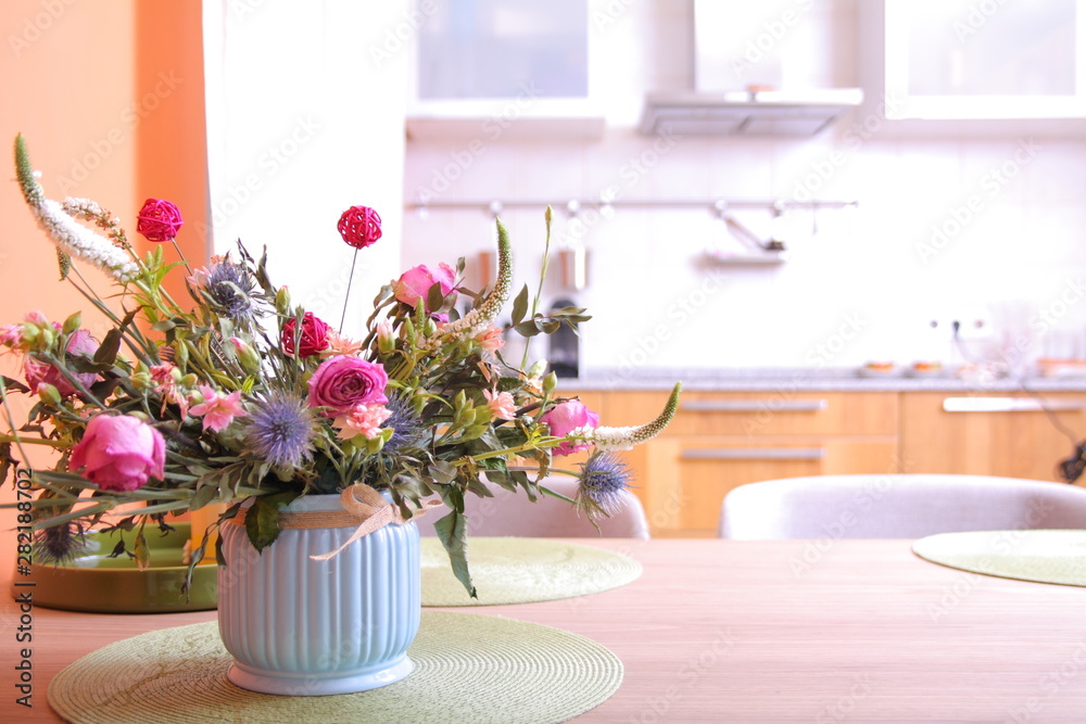 Vase with a bouquet of flowers on a kitchen background