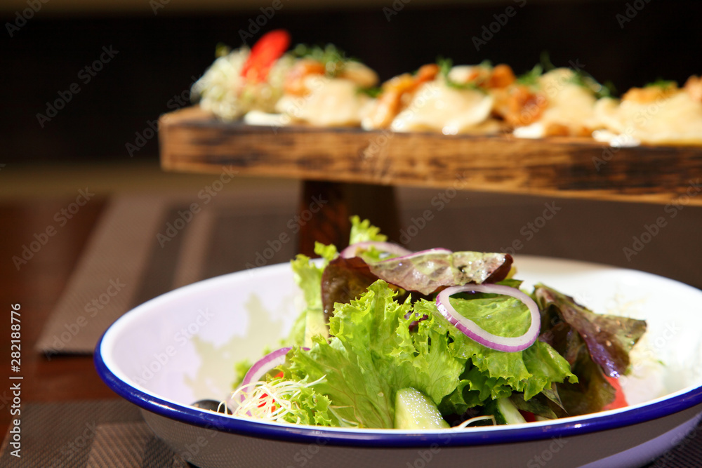 Dumplings with potatoes and greaves in sour cream on a wooden board and salad. Dumplings with potatoes and salad. Dumplings with potatoes and greaves in sour cream on a wooden board and salad. Dumplings with potatoes and salad.
