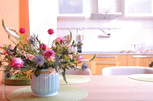Vase with a bouquet of flowers on a kitchen background