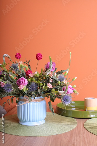 Vase with a bouquet of flowers on a orange wall background