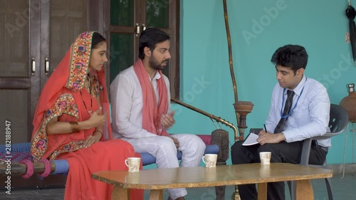 Young government employee collecting information from villagers - survey concept. Indian government official gathering census data from the villagers - Husband and Wife