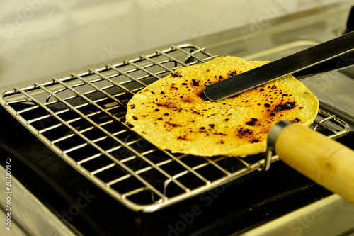 Papad an Indian snack being roasted on a gas stove photo