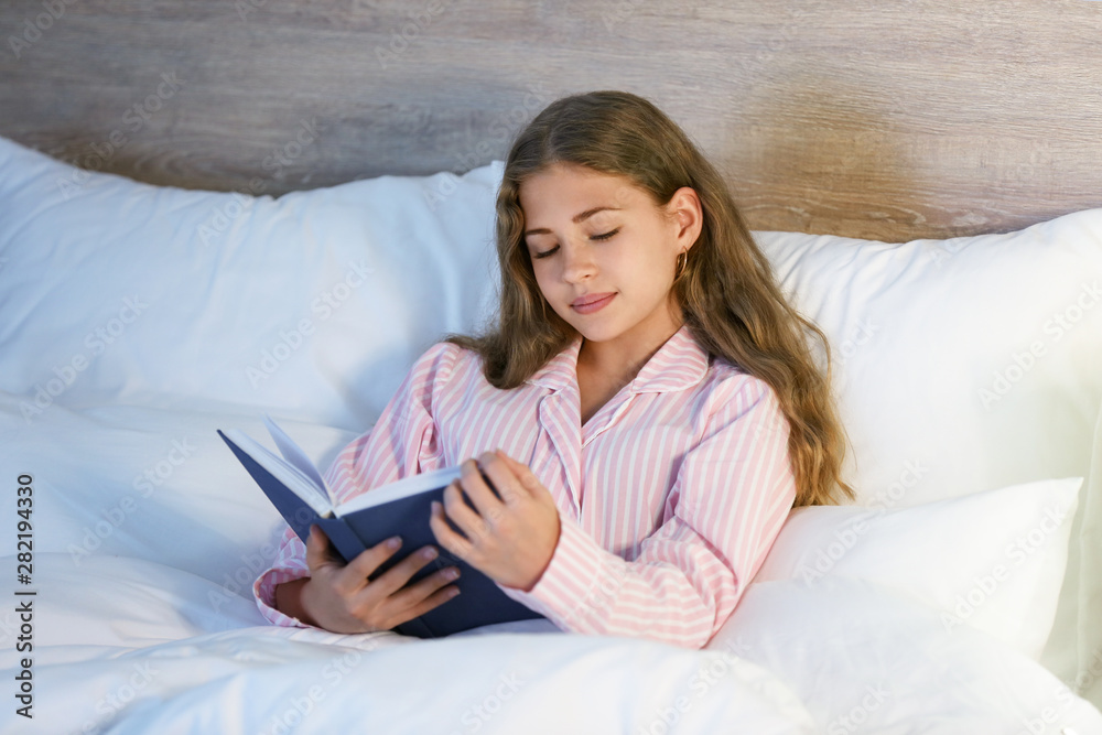 Teenage girl reading book in bed at night Teenage girl reading book in bed at night