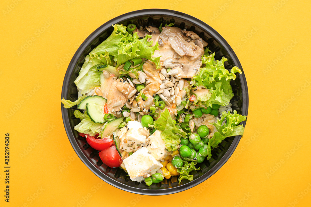 Container with delicious food on color background Container with delicious food on color background