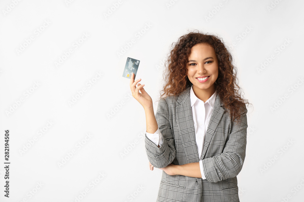 Young African-American businesswoman with credit card on light background Young African-American businesswoman with credit card on light background