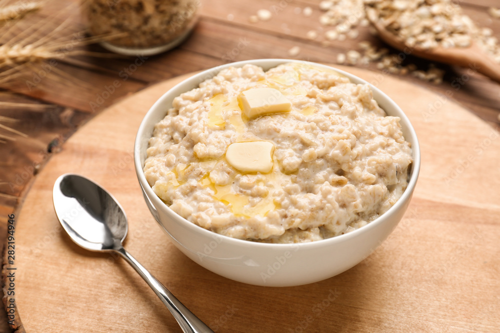 Bowl with tasty oatmeal on wooden board Bowl with tasty oatmeal on wooden board