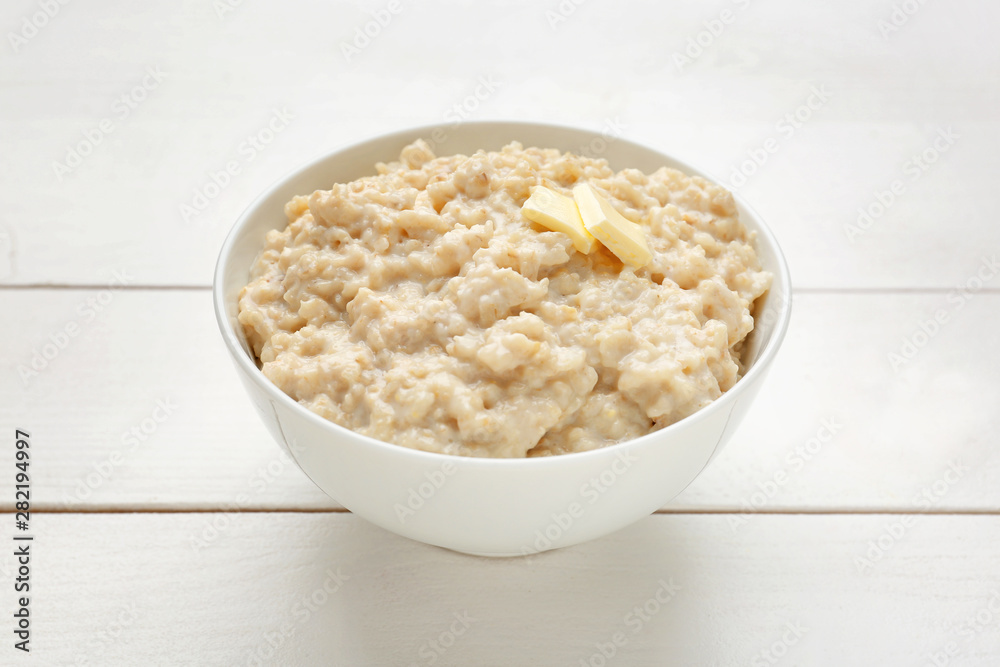 Bowl with tasty oatmeal on white wooden table Bowl with tasty oatmeal on white wooden table