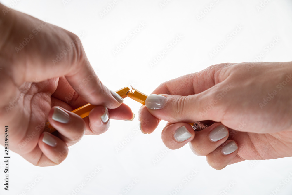 Female hands are breaking yellow pencil on the white background. International Students Day. Female hands are breaking yellow pencil on the white background. International Students Day.