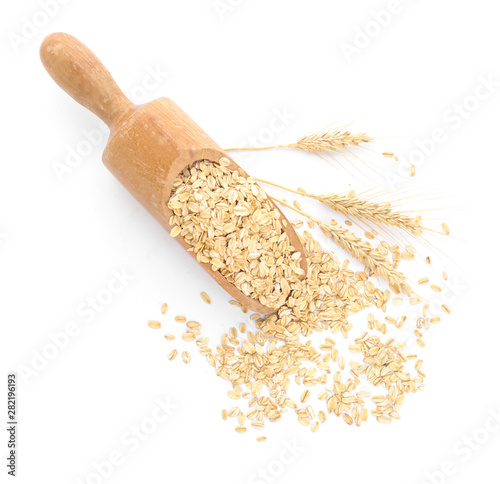 Scoop with raw oatmeal on white background