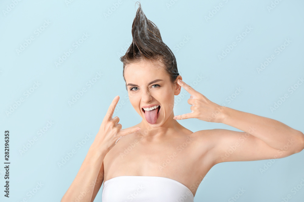 Cool young woman washing hair against color background Cool young woman washing hair against color background
