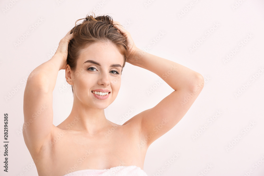 Beautiful young woman after washing hair against light color background Beautiful young woman after washing hair against light color background