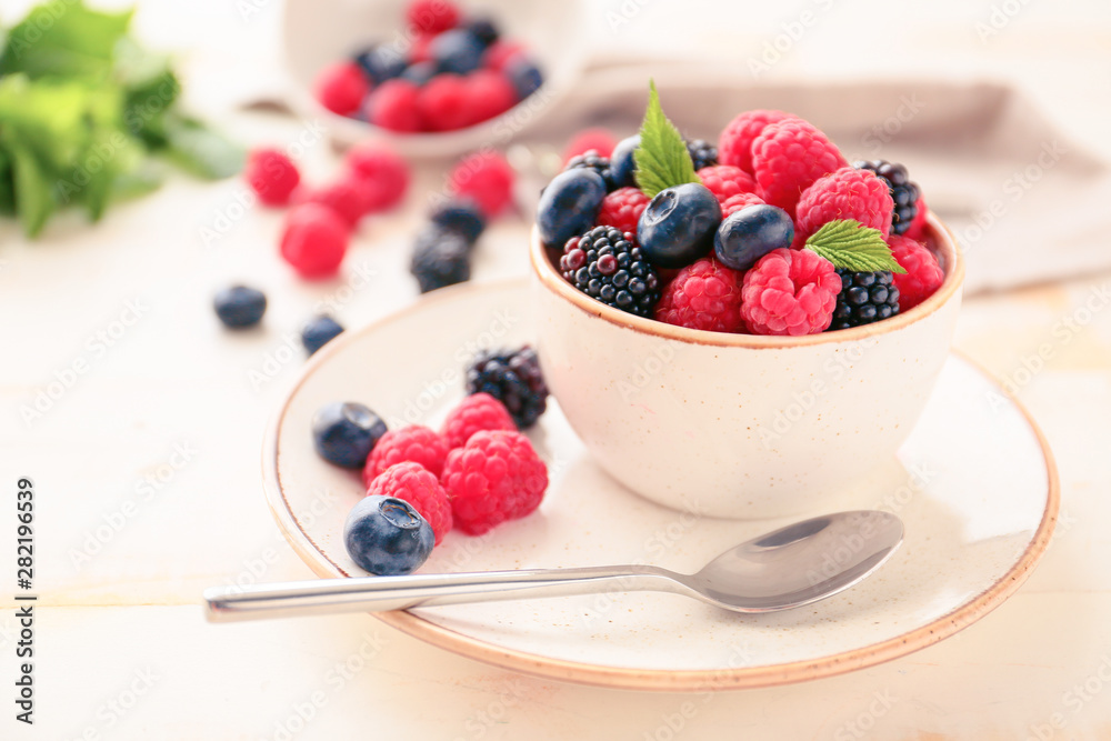 Bowl with tasty ripe berries on table