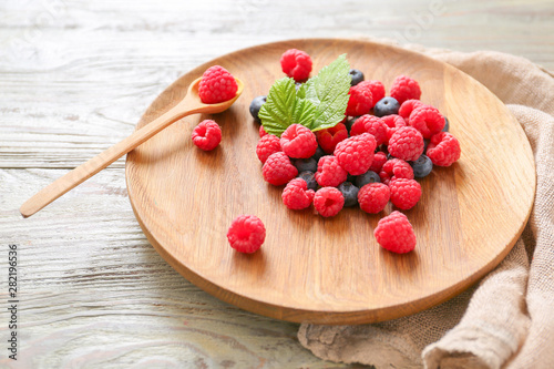 Plate with tasty ripe berries on wooden table