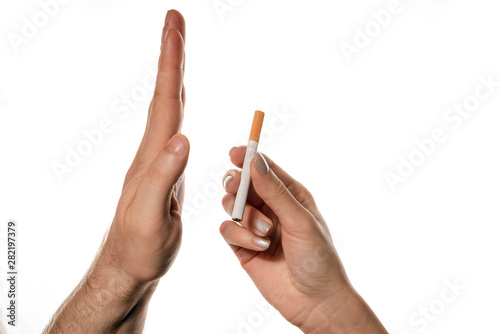 Female hand are giving the cigarette to male hand on the white background/table. Male hand is refusing. No Smoking Day. No Tobacco Day