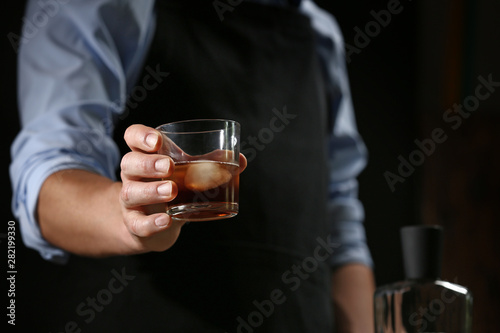 Barman with glass of whiskey in pub, closeup