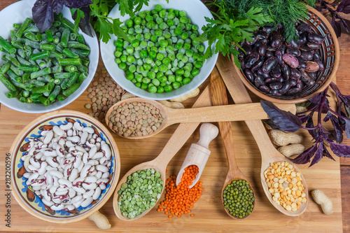 Top view of various uncooked dried and frozen legumes, greens