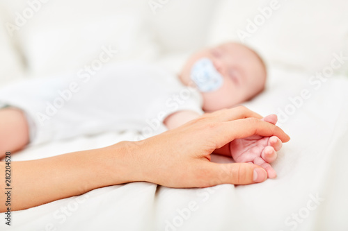 Mom touches hand of sleeping baby