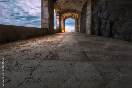 A charming scene taken inside a stone alley with some cloudy sky, symmetric perspective & dreamy effect at Playa de Aro, Spain