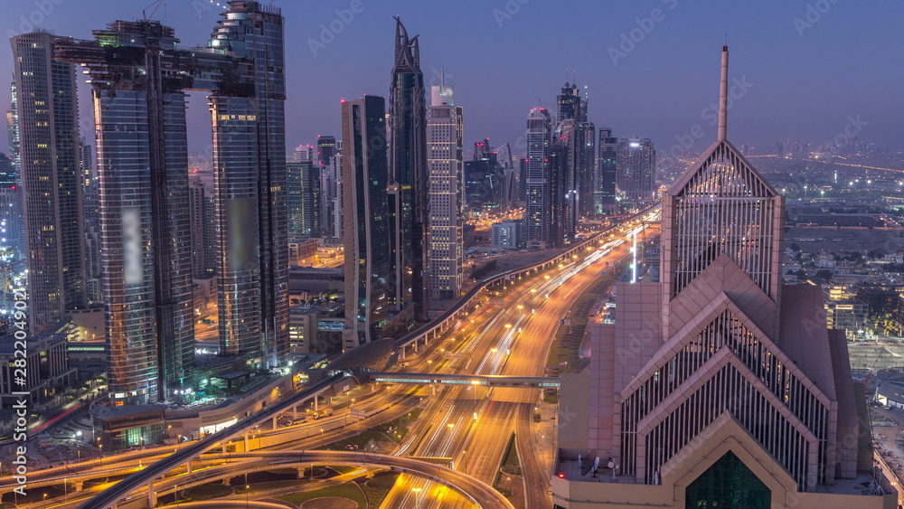 Dubai downtown skyline with tallest skyscrapers and busiest traffic on highway intersection night to day timelapse