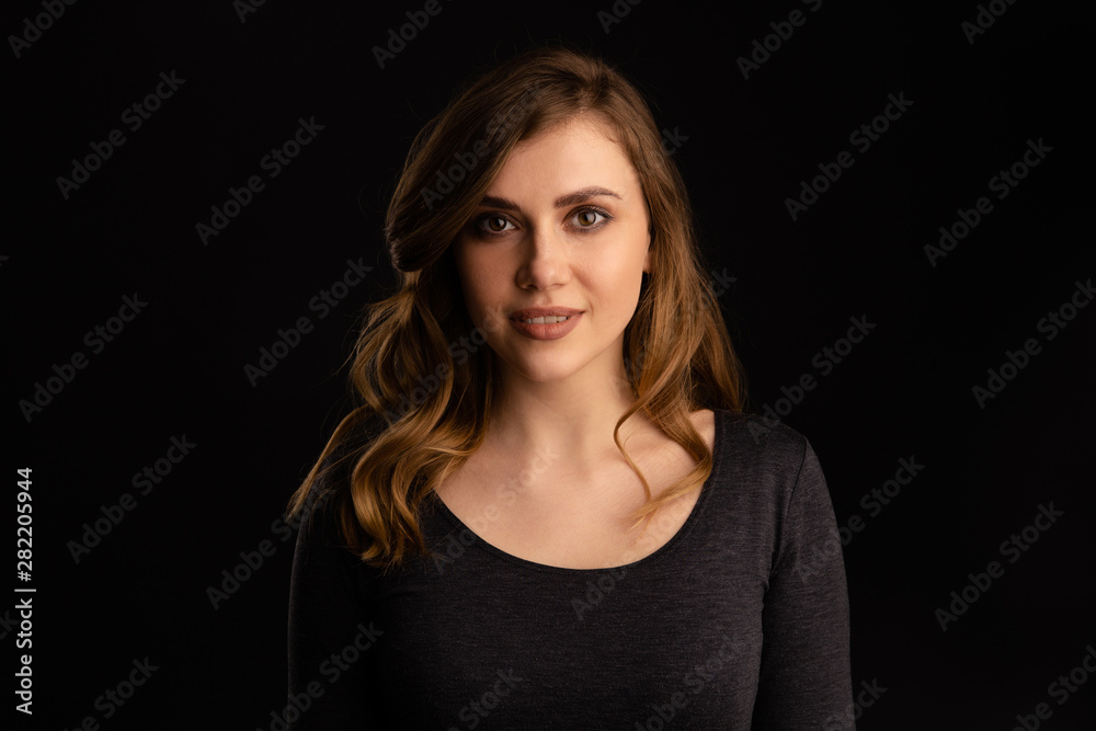 Portrait of smiling young lady with white teeth standing in a studio isolated over the dark background Portrait of smiling young lady with white teeth standing in a studio isolated over the dark background