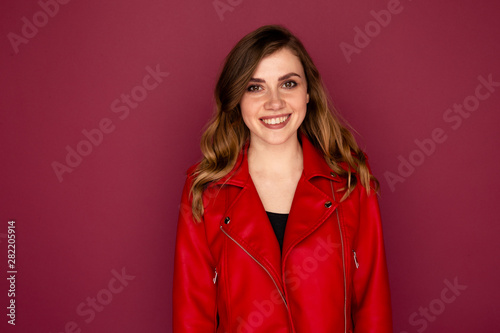 Portrait of pretty young woman in the red clothes isolated over the dark pink background © burdun