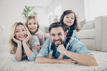 Photo of four members adopted family lying floor toothy smiling fluffy carpet cozy apartments
