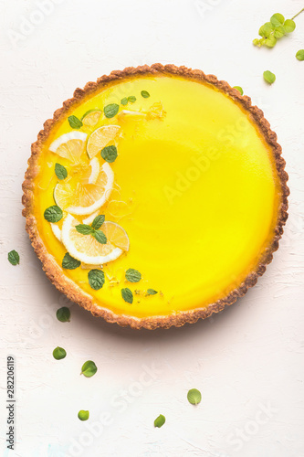 Lemon tart topped with citrus slices and zest on white table background, top view. Copy space. Traditional french cuisine