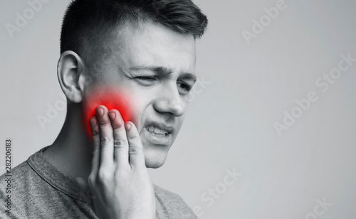 Man suffering from strong tooth pain, monochrome photo