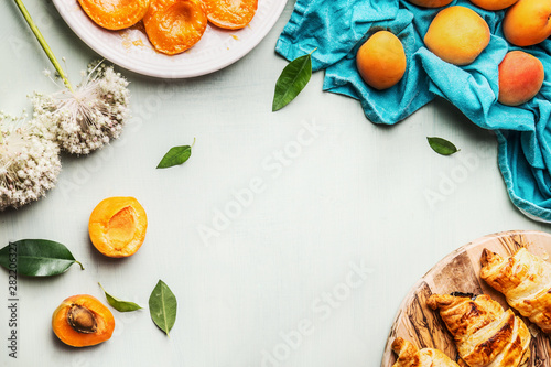 Food background with croissants and apricots to breakfast on light mint background   top view. Frame