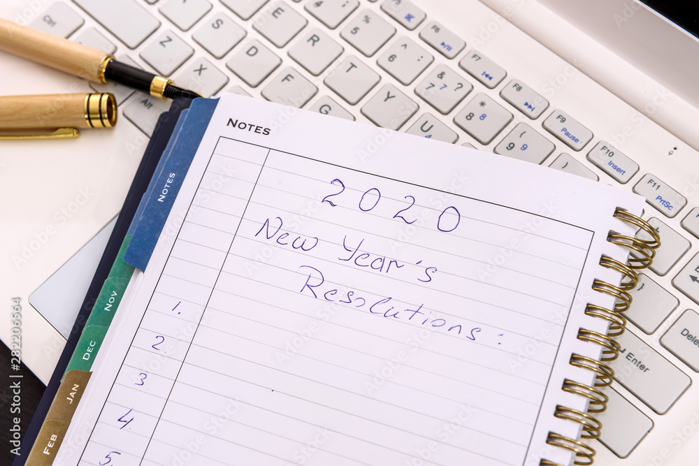 New year resolution in notepad with laptop on table New year resolution in notepad with laptop on table