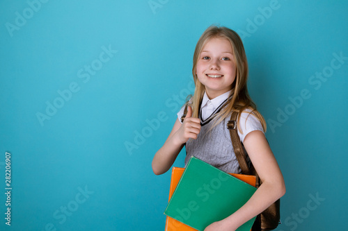 Little girl in a school dress standing isolated the blue background