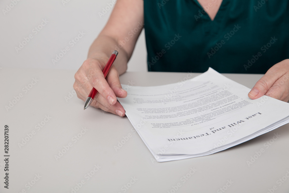 Closeup photo of woman's hands holding paper documents and a pen sitting on the desk Closeup photo of woman's hands holding paper documents and a pen sitting on the desk