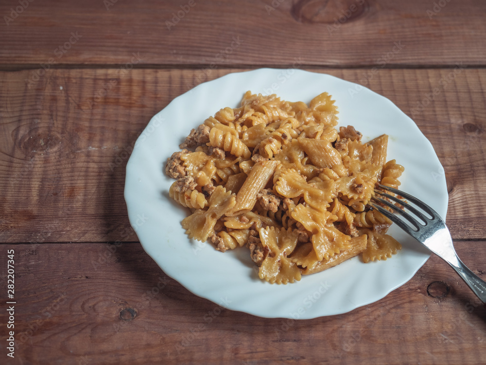Dark flour paste with Turkey minced meat on a white round plate with a fork Dark flour paste with Turkey minced meat on a white round plate with a fork