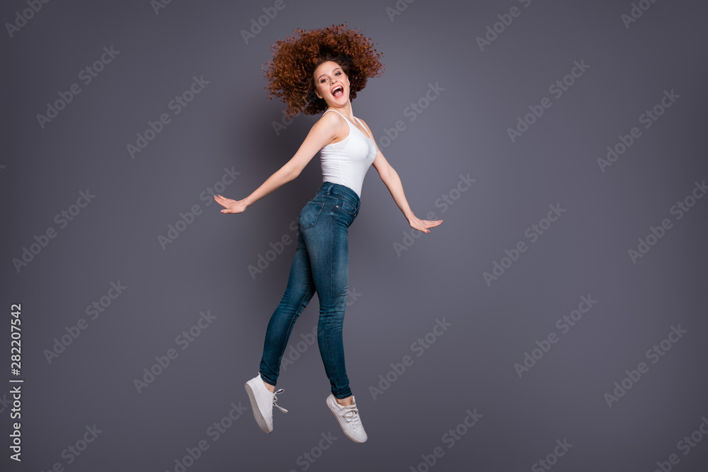 Full length photo of foxy lady jump high amazing yelling wear white tank-top jeans denim pants trousers isolated grey background