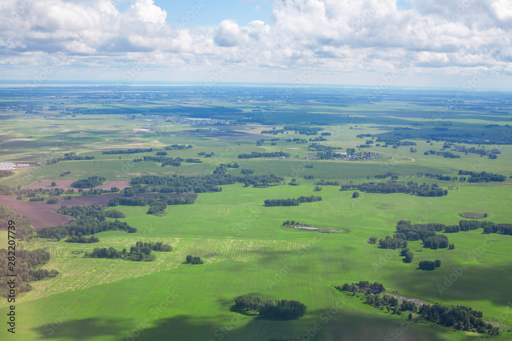Green fields and forests, blue sky and white clouds background panoramic aerial view, sunny summer day europe nature landscape top view, beautiful grassland meadows and trees panorama look from above Green fields and forests, blue sky and white clouds background panoramic aerial view, sunny summer day europe nature landscape top view, beautiful grassland meadows and trees panorama look from above