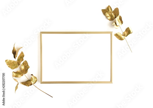 Golden eucalyptus leaves and golden frame mock up om white background isolated top view, flat lay, copy space. Greetings floral minimal card.