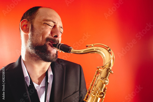 Canvas Print Portrait of professional musician saxophonist man in  suit plays jazz music on s