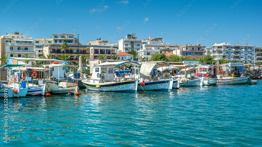 Greek fishing boats in port of Rethymno, Crete island, Greece. View of the port of Rethymno from the sea side with boats and buildings