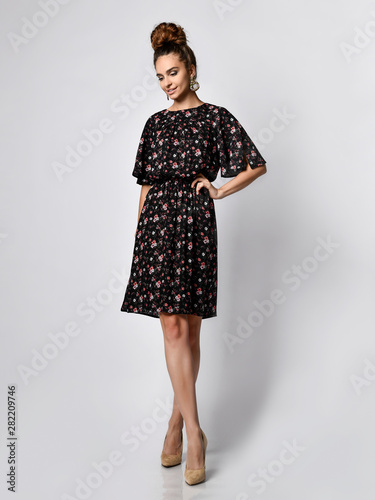 Slim curly female model in a silk pale dress looking at the camera in full growth. Cute girl in romantic clothes is going on a date