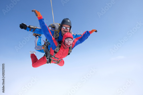 Skydiving. Tandem jump. A strong man and a young woman are falling in the sky.
