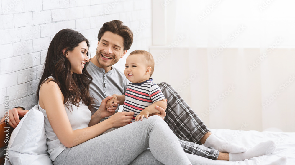 Happy millennial couple enjoying parenthood with adorable baby Happy millennial couple enjoying parenthood with adorable baby